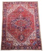 A Heriz red ground carpet, woven central lobed medallion within a floral, geometric field and wide
