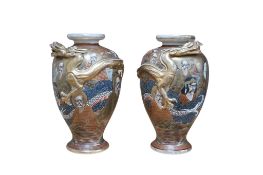 A pair of Japanese Satsuma pottery vases, moulded in relief with dragons, 22cm high