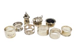 Six assorted silver serviette rings and a silver three piece condiment set.