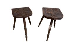 A pair of carved oak armorial shield three legged stools, width 35cm, depth 35cm, height 43cm