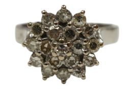 An unmarked white metal and diamond set flowerhead cluster ring, size R, gross weight 6.8 grams.