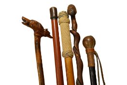 A collection of five walking sticks, one with the handle modelled as a dogs head, another with the