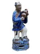 A Chinese pottery figure of a boy holding a basket, late 19th century, 24cm high