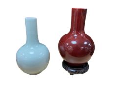 A Chinese sang-de-boeuf glazed bottle vase raised on associated carved hardwood stand, together with