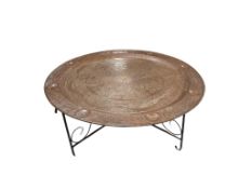 A large Middle Eastern copper tray on a wrought iron stand, tray diameter 97cm, height 40cm