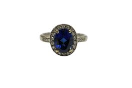 A modern 18ct white gold, synthetic sapphire and diamond set oval cluster ring, with diamond set