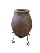 A large Spanish terracotta oil jar, on wrought iron stand, height 170cm