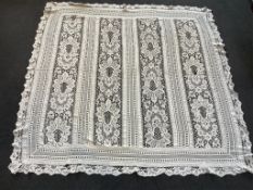 An early 20th century continental cream hand bobbin lace and linen bed cover. Worked in panels of
