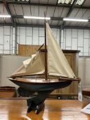 A small 1930's pond yacht, two cotton sails, partially repainted blue hull, of wooden