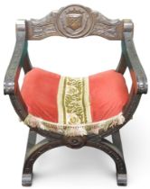A 20th century cross framed Dagobert style armchair with armorial crest carved into backrest over
