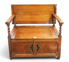 A 20th century oak monks bench with rectangular back/top over shaped arms with barley twist uprights