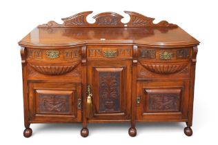 A late Victorian mahogany sideboard with three short drawers over three cabinet doors on ball