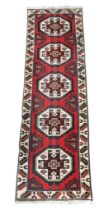 A red ground Heriz runner with five octagonal multicoloured geometric medallions within