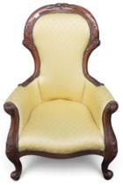 A Victorian walnut framed parlour armchair with gilt yellow upholstery on carved scrolled