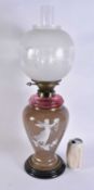 A VICTORIAN PATE SUR PATE ENAMELLED OIL LAMP painted with a fairy holding a floral wreath. 58 cm