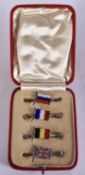 A CASED SET OF SILVER AND ENAMEL FLAG PINS. 13.8 grams. Each 4 cm wide.