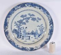 A MONUMENTAL 18TH CENTURY CHINESE EXPORT BLUE AND WHITE DISH Qianlong, painted with two figures in a