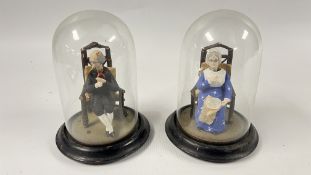 A MATCHED PAIR OF VINTAGE NODDING FIGURES EACH SEATED UNDER A GLASS DOME, H 19CM.