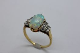 AN UNMARKED DECO STYLE OPAL AND DIAMOND LADIES RING, THE CENTRAL OVAL OPAL APPROX 12MM X 7MM,