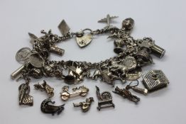A SILVER CHARM BRACELET WITH FORTY SEVEN CHARMS (9 CHARMS DETACHED).