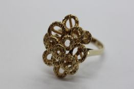 A 9CT GOLD RING OF ABSTRACT DESIGN OF PIERCED CIRCLES.