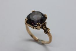 AN UNMARKED AMETHYST SET DRESS RING, THE STONE CLAW SET.