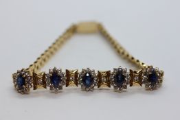 AN ELABORATE DRESS BRACELET SET WITH FIVE BLUE AND WHITE SAPPHIRE CLUSTERS STAMPED 750, L 19CM.