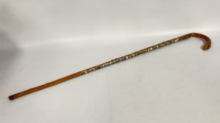 A VINTAGE WALKING STICK BEARING VARIOUS SOUVENIR BADGES.