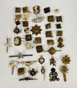 A TUB CONTAINING AN ASSORTMENT OF VINTAGE CAP BADGES TO INCLUDE MILITARY EXAMPLES ETC.