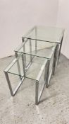A NEST OF 3 GRADUATED DESIGNER GLASS AND CHROME OCCASIONAL TABLES.