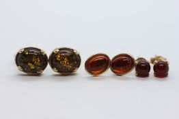 A PAIR OF 9CT GOLD AMBER TYPE STUD EARRINGS + TWO FURTHER PAIRS OF YELLOW METAL EXAMPLES.