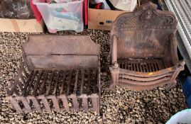 TWO VINTAGE CAST IRON FIREPLACES, ONE FEATURING AN ORNATE BACK PLATE.