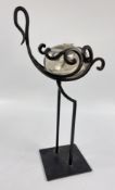 A DECORATIVE WROUGHT IRON BIRD SCULPTURE SUPPORTING A CLEAR GLASS BODY POSSIBLY A CANDLE HOLDER,