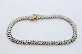 A 9CT YELLOW AND WHITE GOLD DIAMOND SET TENNIS BRACELET, L 19CM.