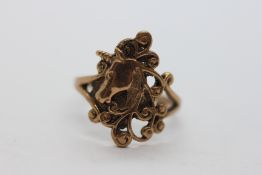 AN UNMARKED YELLOW METAL OPEN WORK UNICORN RING.
