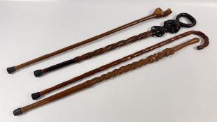 A GROUP OF 4 CARVED WOODEN WALKING STICKS TO INCLUDE ETHNIC / AFRICAN EXAMPLES.