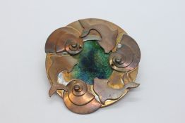 AN ARTS AND CRAFTS STYLE BROOCH DEPICTING A DOLPHIN & SHELL DESIGN WITH AN ENAMEL CENTRAL PANEL.