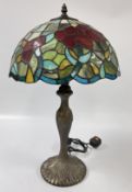 A DECORATIVE TIFFANY STYLE LAMP AND SHADE FEATURING A LEADED GLASS DESIGN WITH A FLORAL PATTERN,