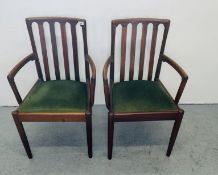 A PAIR OF TEAK FRAMED ELBOW CHAIRS BY MERRYDEW FURNITURE WITH SLAT RAILS TO BACK REST AND GREEN