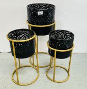 A SET OF THREE GRADUATED METAL CRAFT PLANTERS IN STANDS,THE TALLEST 53CM.