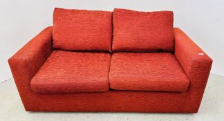 A MODERN RED UPHOLSTERED TWO SEATER SOFA BED.
