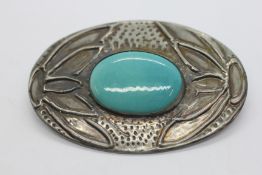 AN ARTS AND CRAFTS STYLE BROOCH INSET WITH AN OVAL TURQUOISE PANEL.