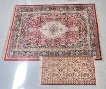 KASHMIR SILKRON FIBRE BURGUNDY CARPET 180CM X 230CM AND ONE OTHER SMALL WOVEN RUG ON RED GROUND.