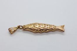 A YELLOW METAL FISH PENDANT.