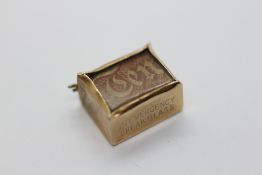 A 9CT GOLD CHARM, THE ATTACHMENT LOOP AS FOUND, CONTAINING AN OLD TEN SHILLING NOTE.