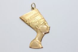 AN EGYPTIAN YELLOW METAL PENDANT IN THE FORM OF A PHARAONIC HEAD.