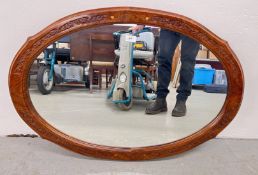 AN OVAL WALL MIRROR IN A CARVED HARD WOOD FRAME, W 90CM, H 63CM.