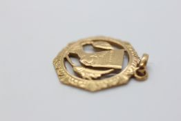 AN EGYPTIAN GOLD PENDANT, THE CIRCULAR FRAME ENCLOSING A PHARAONIC HEAD.