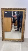 A DECORATIVE GILT FRAMED WALL MIRROR WITH BEVELLED GLASS.