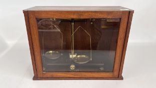 A SET OF VINTAGE BALANCE SCALES IN A FITTED GLAZED MAHOGANY CASE.